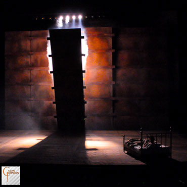 "Angels In America" at Carnegie Mellon. Beams of bright light shine down on Prior Walter while laying in bed as the wall falls around him.