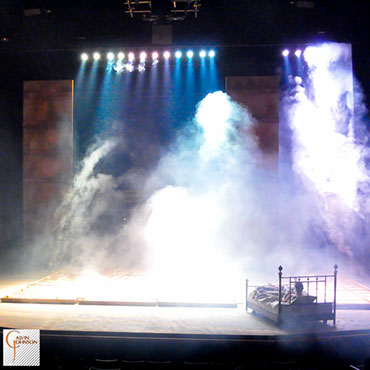 Beams of bright light shine down on Prior Walter while laying in bed as the wall falls around him.