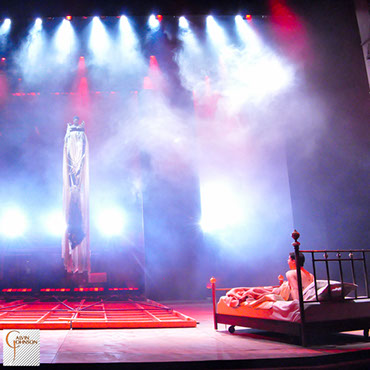 "Angels In America" Bright red and white beams of light shine down on Prior Walter lying in bed after the wall has fallen and the Angel decends.