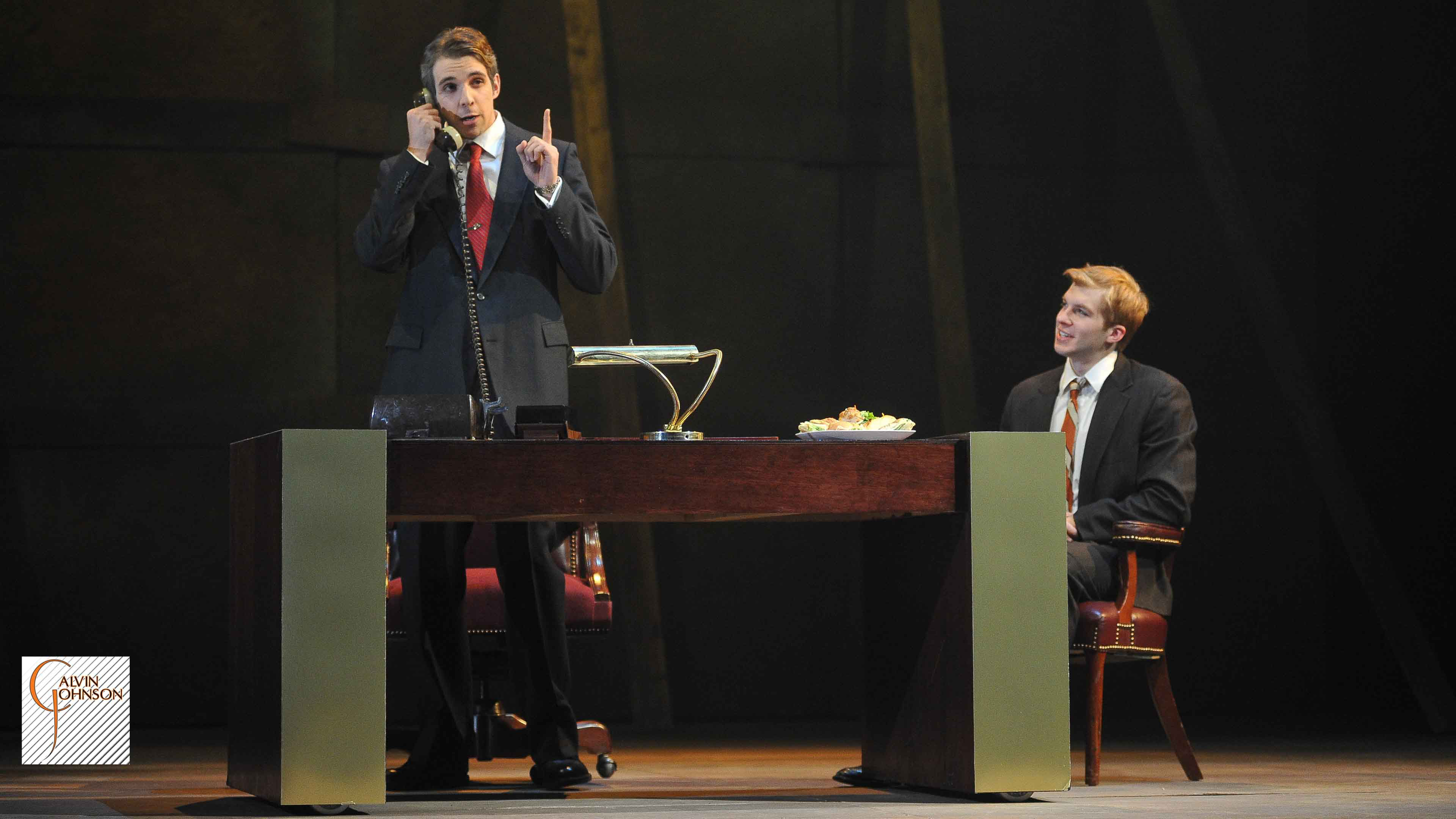 A performance of "Angels In America" at Carnegie Mellon. Roy Cohn Talks on the phone while Joe Pitt waits at his desk.