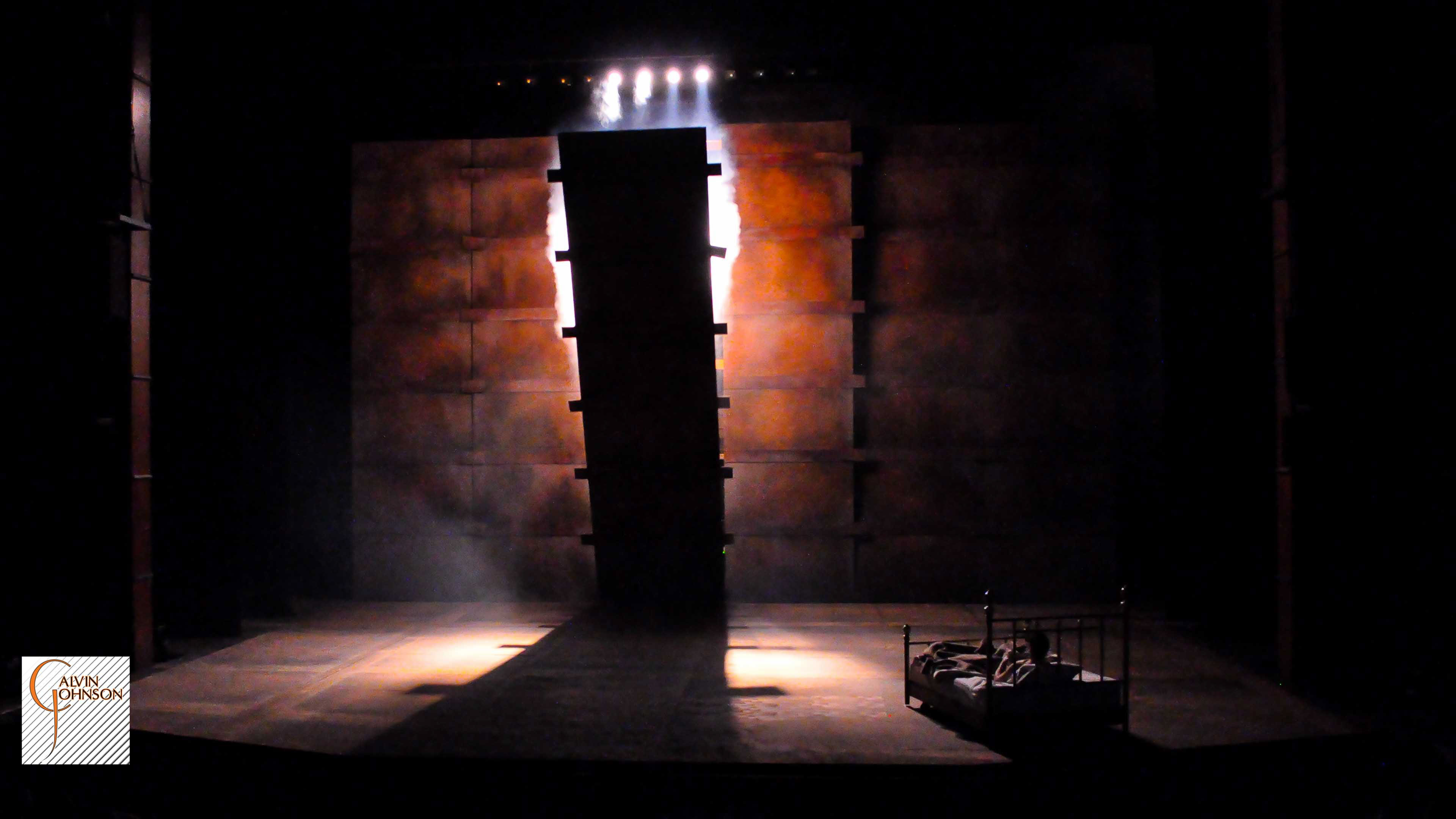 "Angels In America" at Carnegie Mellon. Beams of bright light shine down on Prior Walter while laying in bed as the wall falls around him.