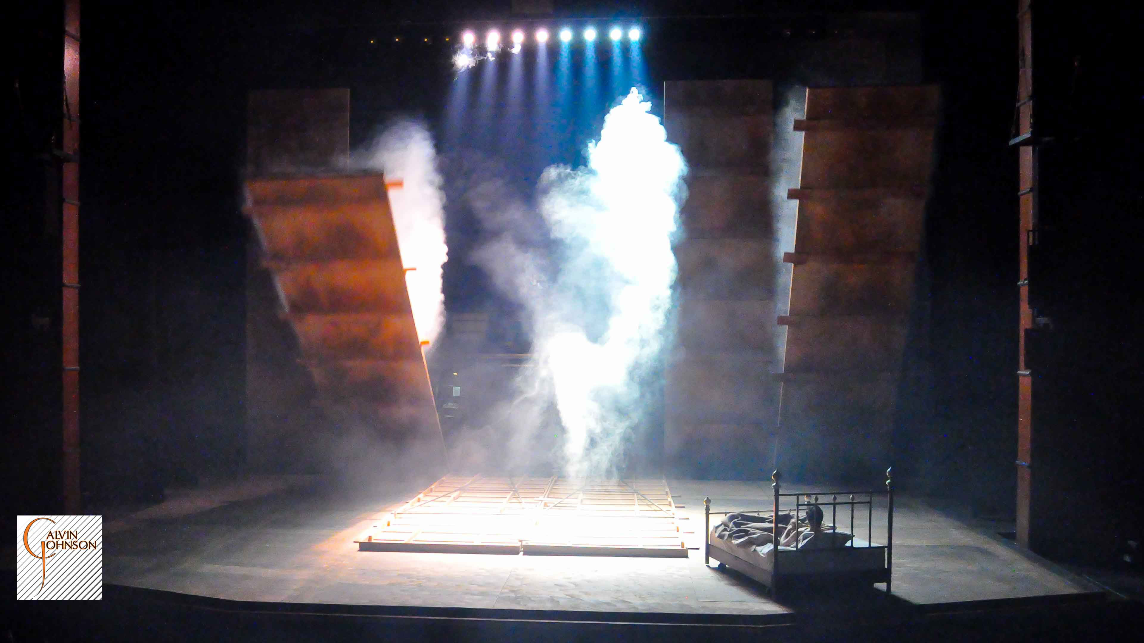 "Angels In America" at Carnegie Mellon. Beams of bright light shine down on Prior Walter while laying in bed as the wall falls around him.