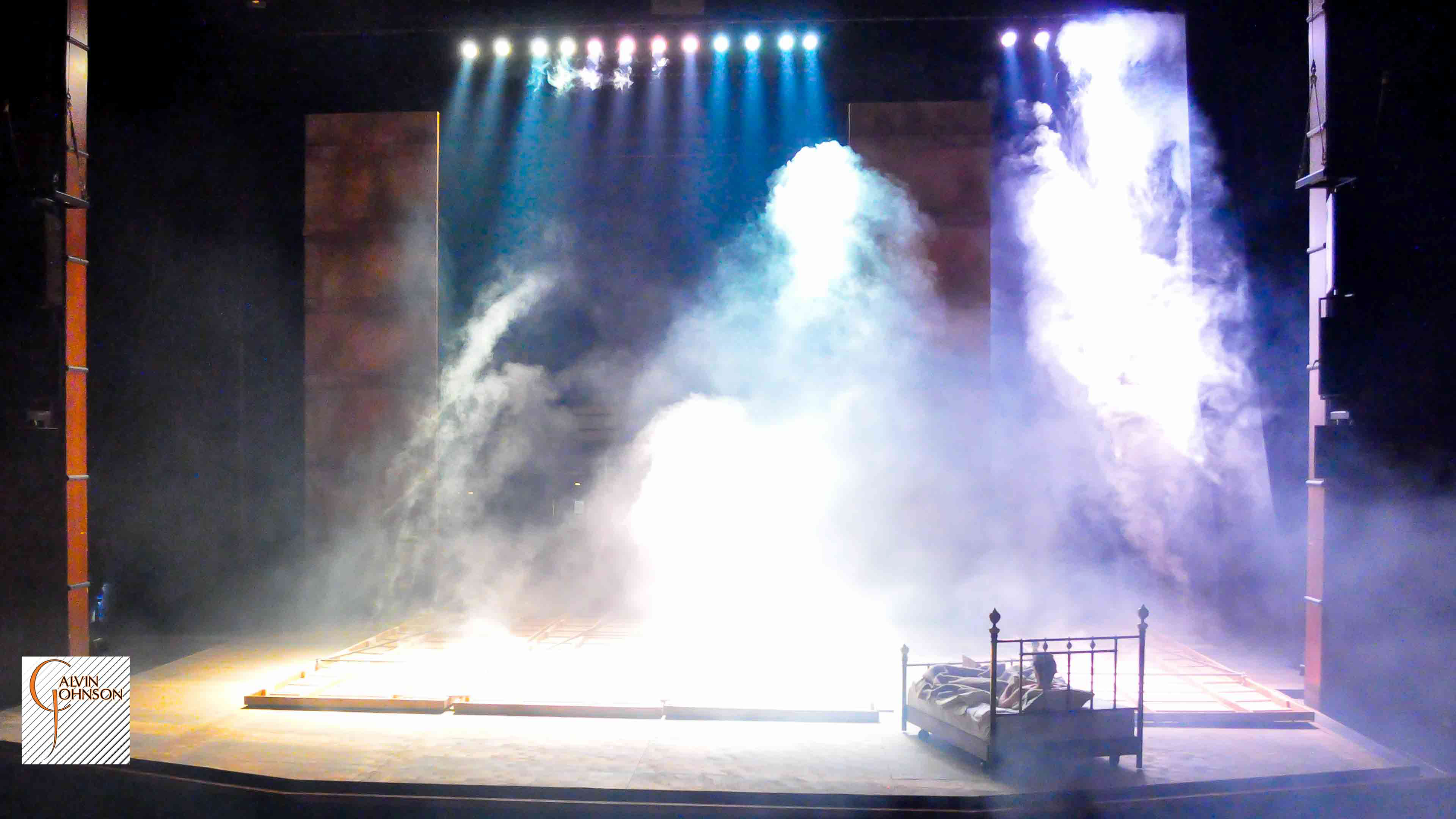 Beams of bright light shine down on Prior Walter while laying in bed as the wall falls around him.