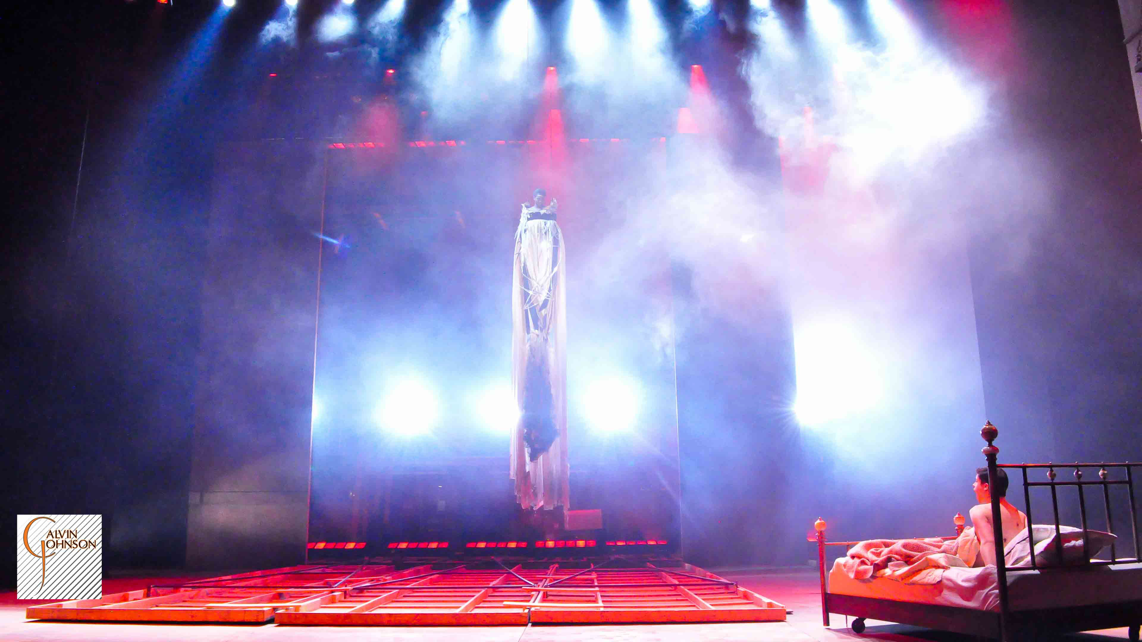 "Angels In America" Bright red and white beams of light shine down on Prior Walter lying in bed after the wall has fallen and the Angel decends.