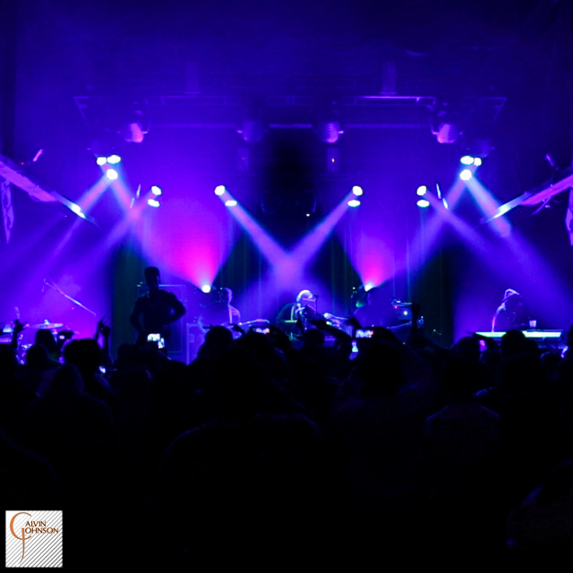 Hip Hop artist B.o.B performing in front of purple beams of light at a concert with DJ Shawty Slim.