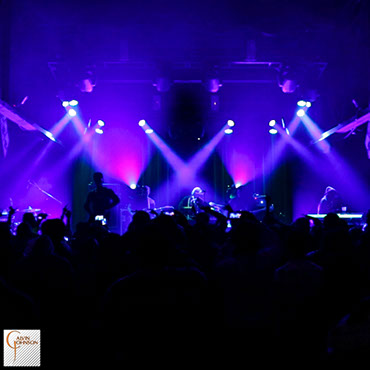 Hip Hop artist B.o.B performing in front of purple beams of light at a concert with DJ Shawty Slim.