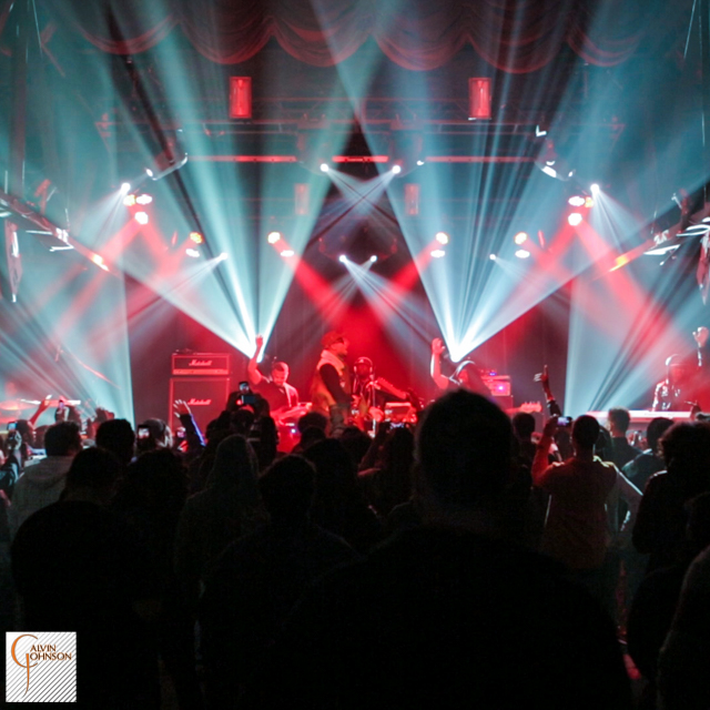 Hip Hop artist B.o.B performing in front of white and red beams of light at a concert with DJ Shawty Slim.