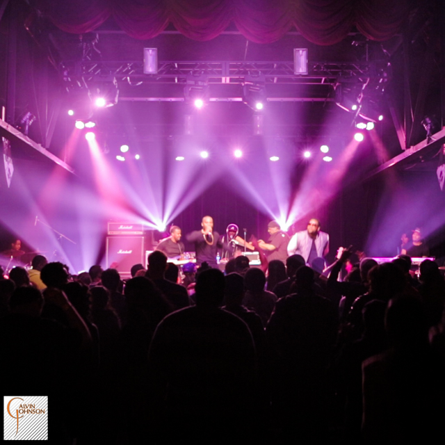 Hip Hop artist B.o.B performing in front of magenta and pink beams of light at a concert with DJ Shawty Slim.