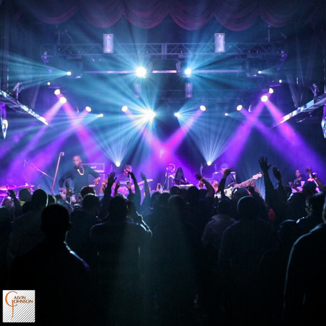 Hip Hop artist B.o.B performing in front of purple and blue beams of light at a concert with DJ Shawty Slim.