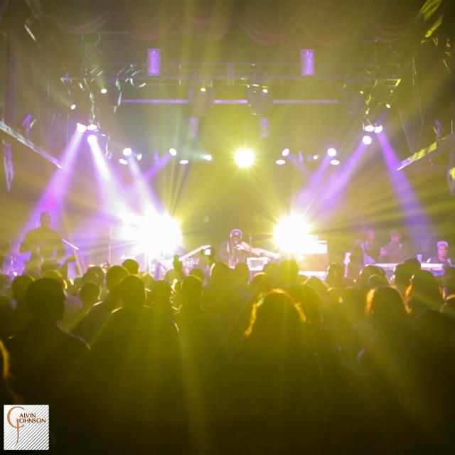 Hip Hop artist B.o.B performing in front of purple and white beams of light at a concert with DJ Shawty Slim.