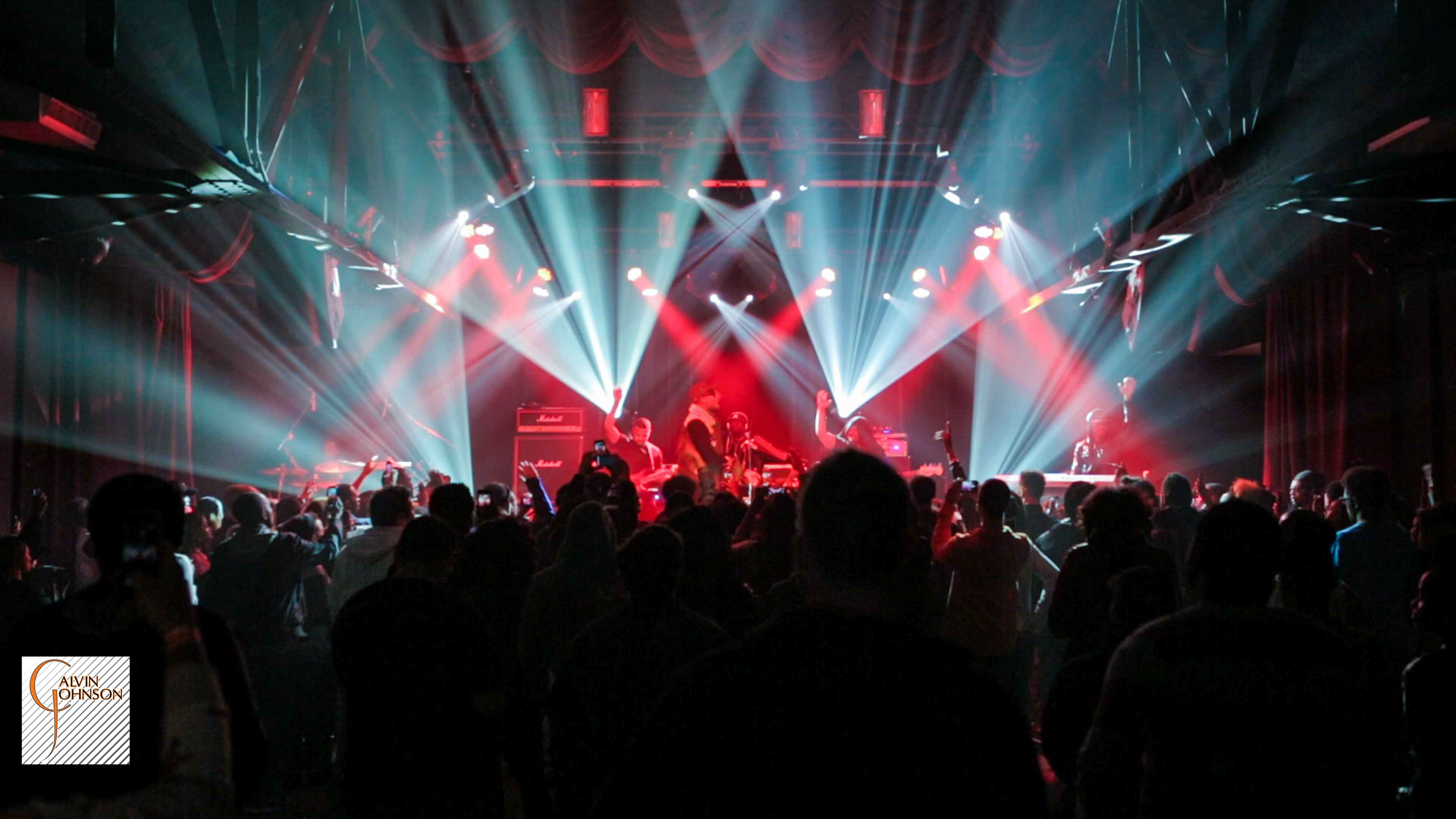 Hip Hop artist B.o.B performing in front of purple and green beams of light at a concert with DJ Shawty Slim.
