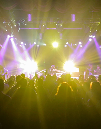 Hip Hop artist B.o.B performing in front of purple and green beams of light at a concert with DJ Shawty Slim.