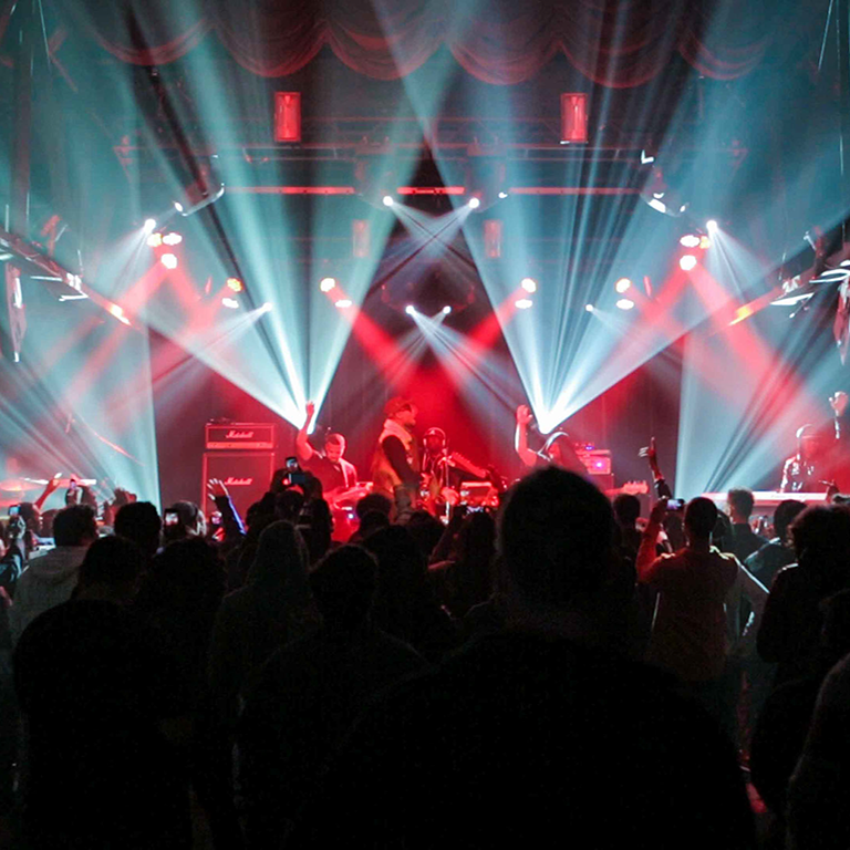 Hip Hop artist B.o.B performing in front of purple and green beams of light at a concert with DJ Shawty Slim.