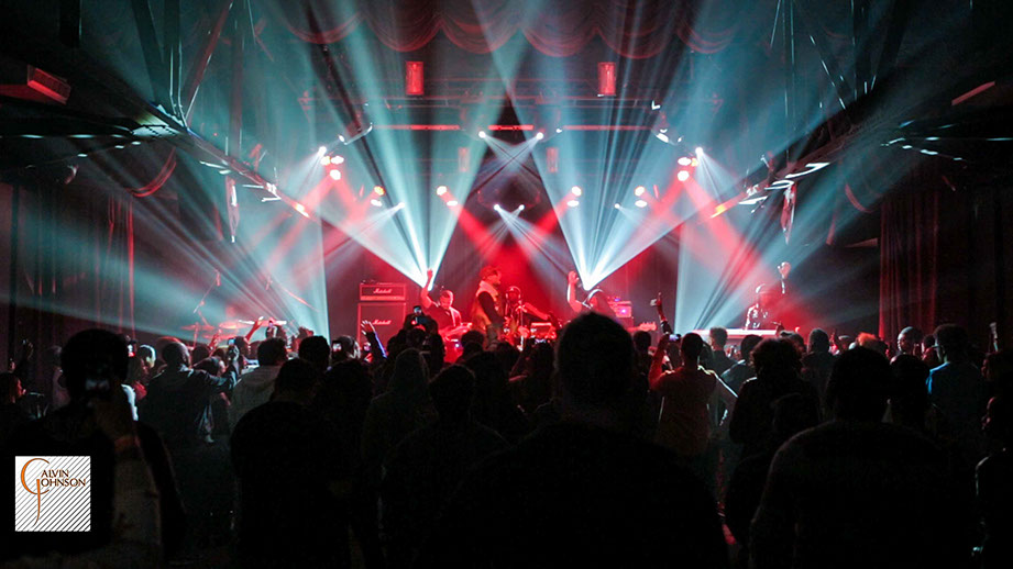 Hip Hop artist B.o.B performing in front of purple and green beams of light at a concert with DJ Shawty Slim.