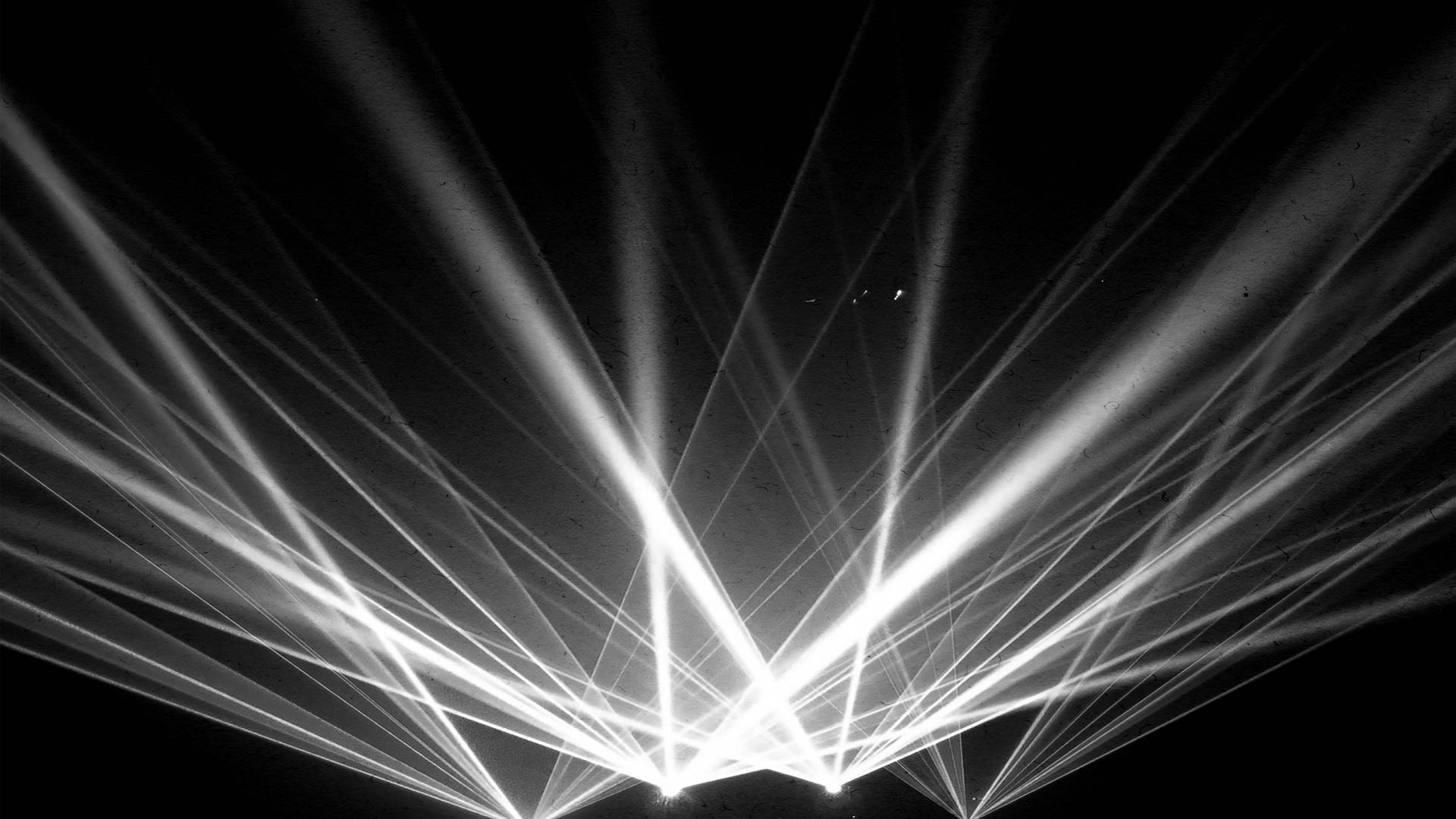 Laser light beams projecting upward from the bottom center of the screen into the darkness above.